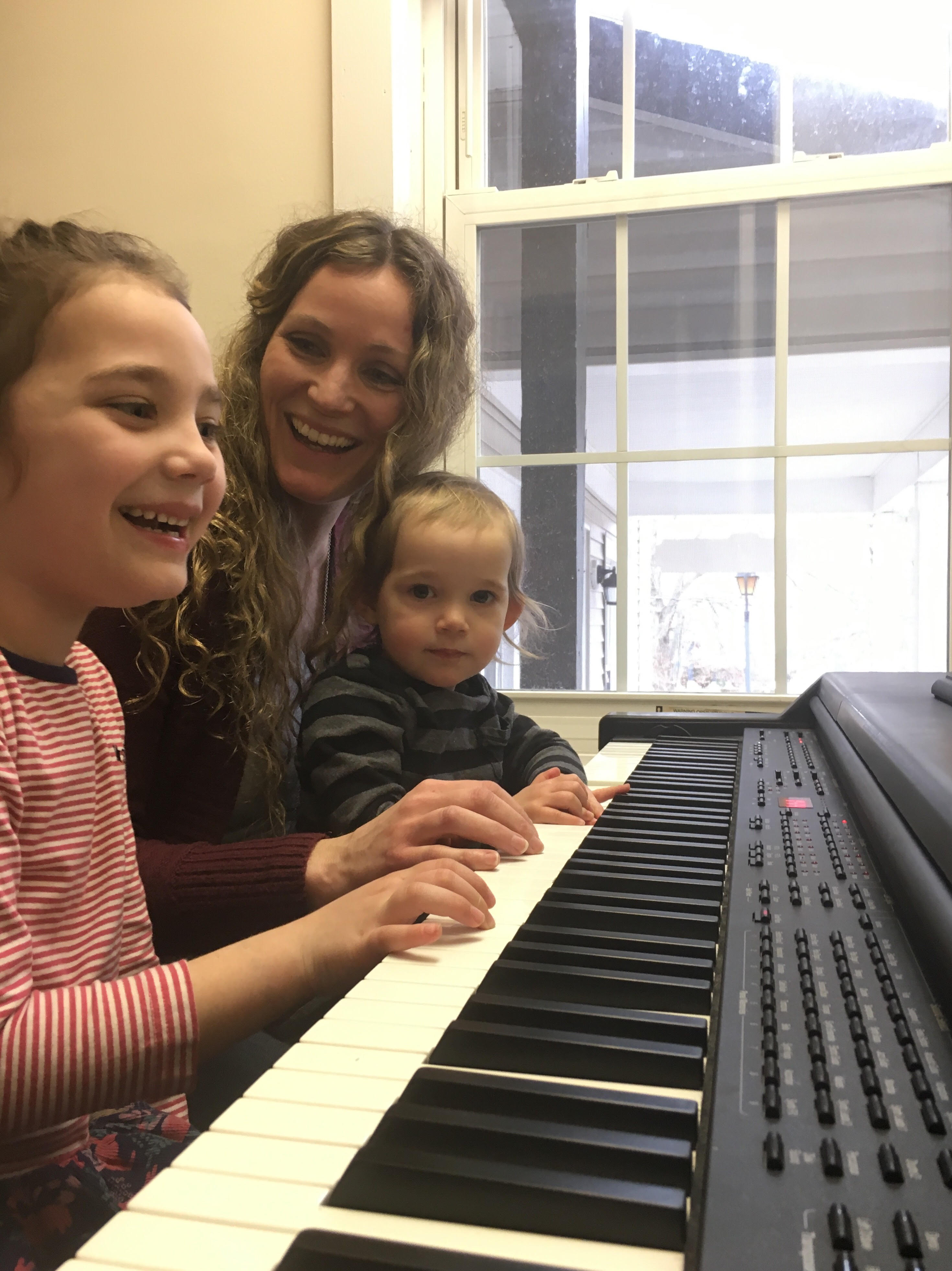 mother and two children playing piano